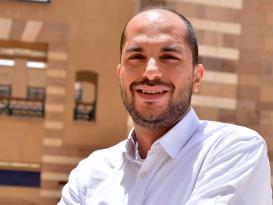 Man wearing a white shirt smiling with his hands crossed