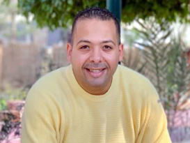 a man smiling wearing a yellow shirt