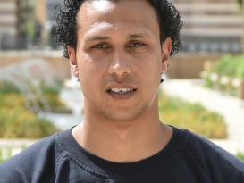 Headshot of a man wearing a black sweatshirt in an outdoor setting