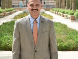 Man smiling wearing a suit and tie in an outdoor setting