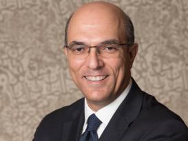 Man in dark suit and glasses smiling
