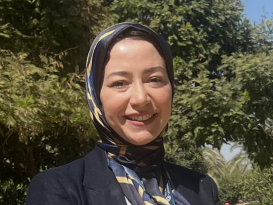 A veiled woman is standing and smiling