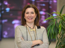 a headshot of a woman with short brown hair having her hands crossed and smiling at the camera
