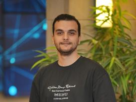 a man wearing a black tshirt with short black hair and smiling