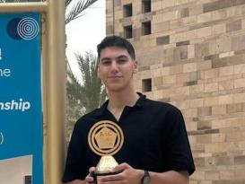 A male is smiling. He is holding an award