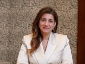 A woman is sitting at a table and she is smiling