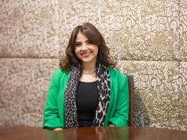 A female is siting down and smiling  