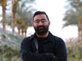 a headshot for a man with a black hair and a dark jeans jacket with a black tshirt