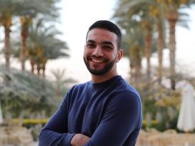 a headshot of a man wearing a navy shirt with short dark brown hair