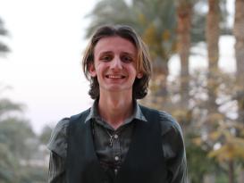 a headshot for a man with a light brown hair wearing a green chemise and dark green vest