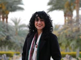 a headshot for a girl with a dark curly hair wearing black jacket