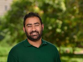 a headshot of a man wearing a green tshirt with black hair and black beard