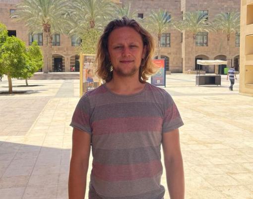 A male student wearing a striped t-shirt on campus
