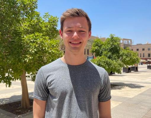 A male student wearing a grey t-shirt on campus