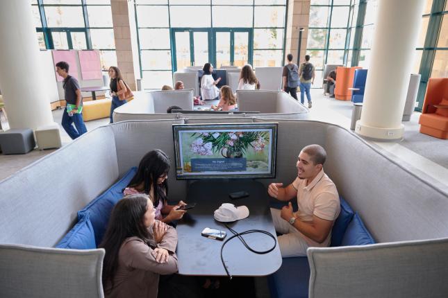 Three students sitting in a booth in the newly renovated library.