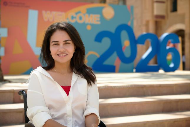 A girl posing to the camera right next to a massive Fall 2026 decoration