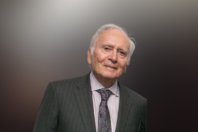 Arthur Lindenauer in a suit in front of a mixed light background