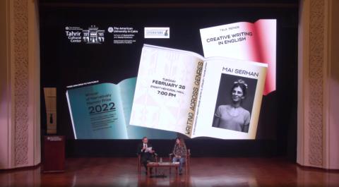 Open books and a man and a woman sitting on stage