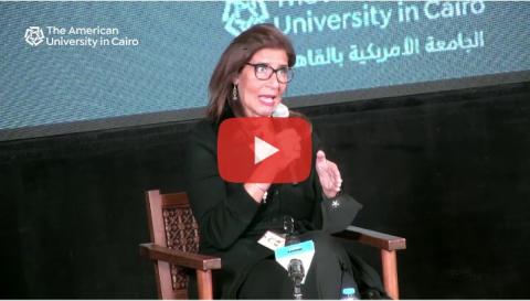 A woman sitting on a chair and talking into a microphone