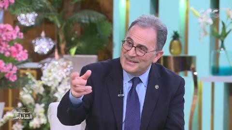 A man talking, wearing a suit and glasses