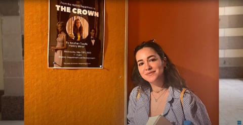 A woman leaning on a wall that has "The Crown" series poster
