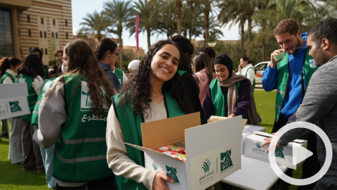 Students carrying cardboard boxes, text reads "متطوع، التحالف الوطني"