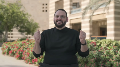 A man is talking. He is wearing glasses and lifting his fists up happily