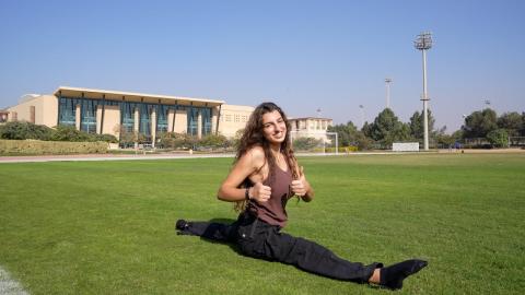 A female athlete doing a gymnastics split in a field