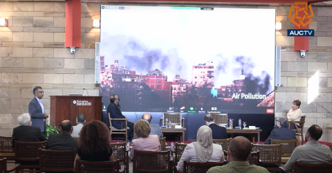 Faculty member Khaled Tarabieh. He is standing n a conference room in front of an audience and a screen. Text: Air Pollution. AUCTV and the AUC star