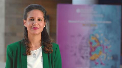 A woman is smiling and there is a colorful background behind her