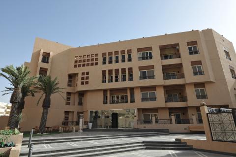 Tall beige building with palm trees