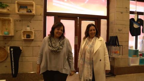 Two women standing in a clothes shop and they are smiling