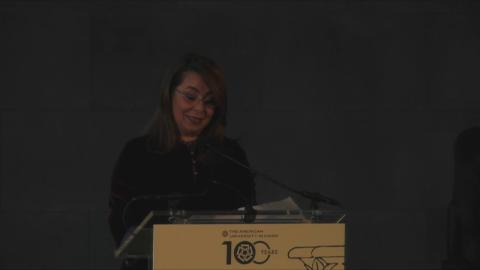 A woman is standing at a podium talking into a microphone