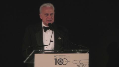 A man is standing at a podium talking into a microphone