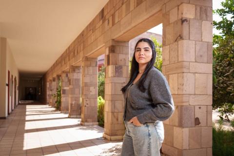 A female is standing, she has her hands in her pockets