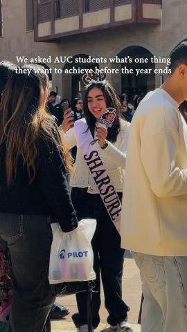 Students standing and laughing. Text: We asked AUC students what's one thing they want to achieve before the year's end