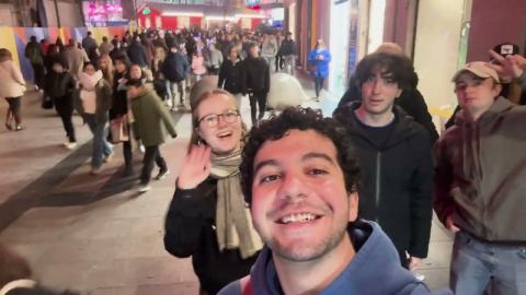 Males and females are waving and smiling in the street