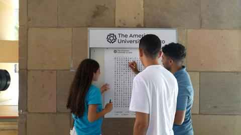 Two males and one female solving a word search puzzle