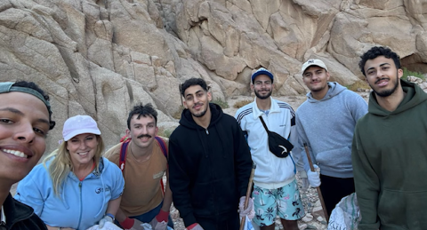 A group of people are standing in front of a mountain and smiling