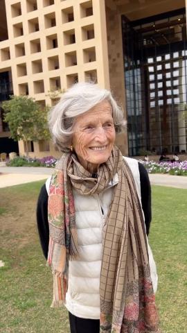 A woman is standing in a garden and smiling