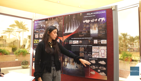 A female is standing in front of a board and pointing at it
