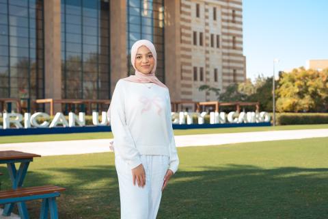 A veiled female dressed in white is standing and smiling