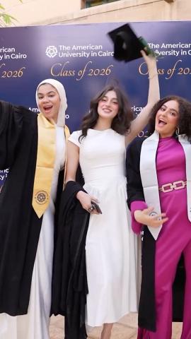 Three females are standing and smiling. They are wearing their graduation caps and gowns