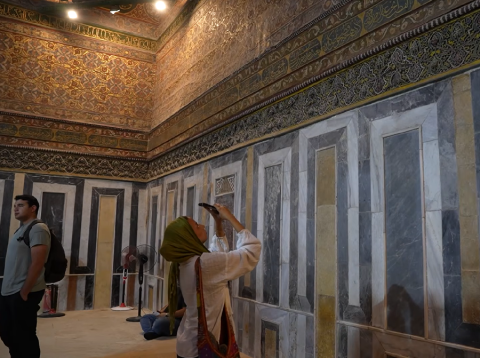 A woman is in a mosque taking photographs of the architecture