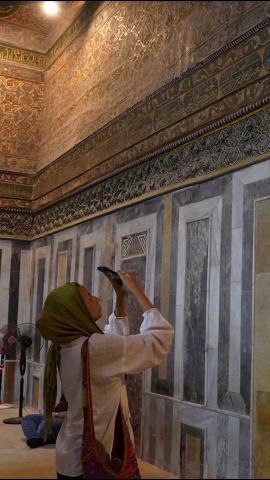 A woman is in a mosque taking photographs of the architecture