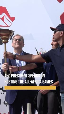 A male is lighting a torch and two people are holding it for him. Text: AUC President speaks on hosting the All-Africa Games