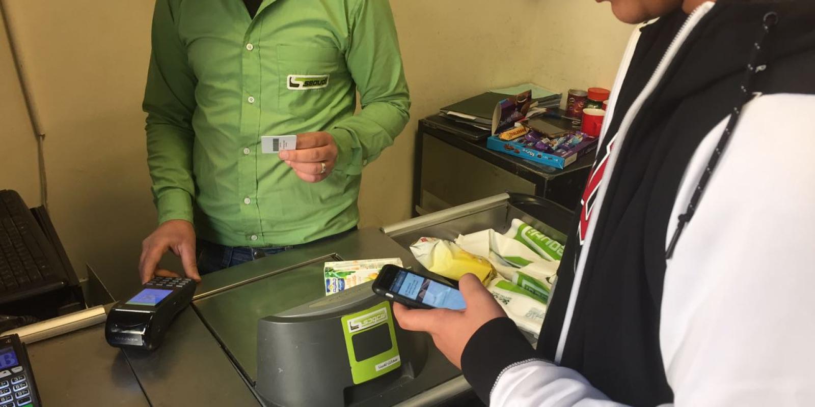 a student using his ID to buy something from a cashier across the counter