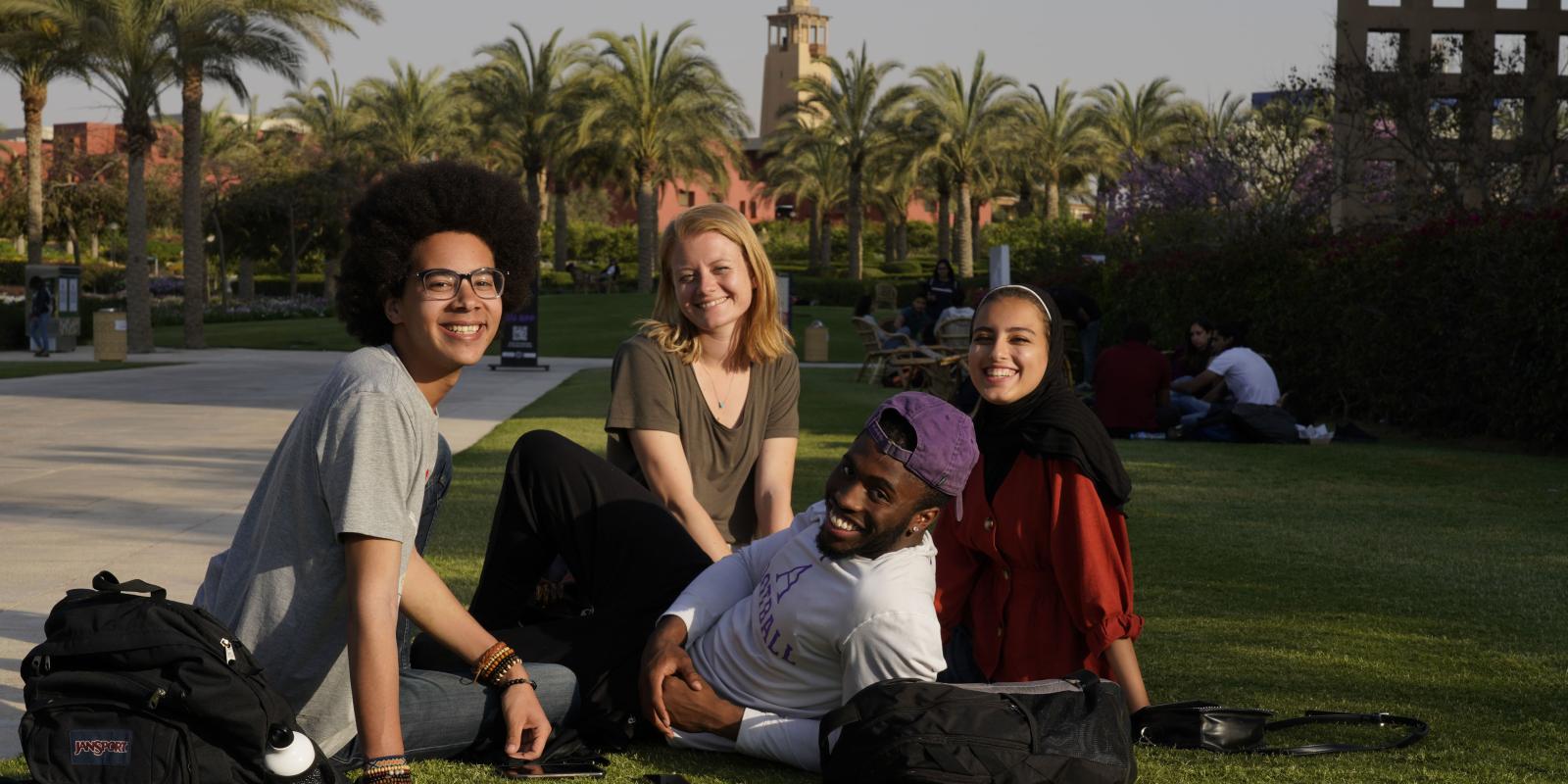 AUC international students sitting in the campus gardens. 