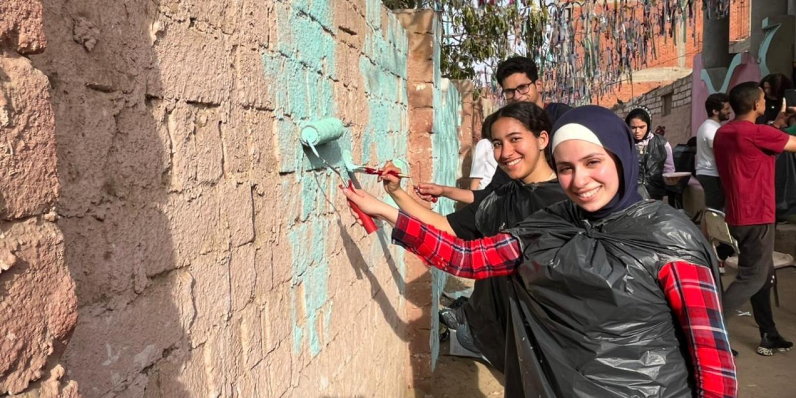 AUC student volunteers paint walls near a home in Fayoum