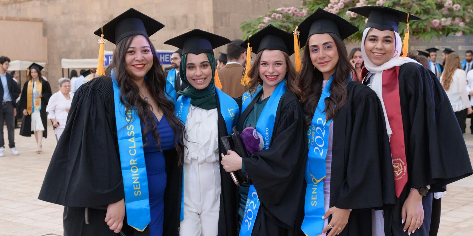 group of smiling girls with cap and gown